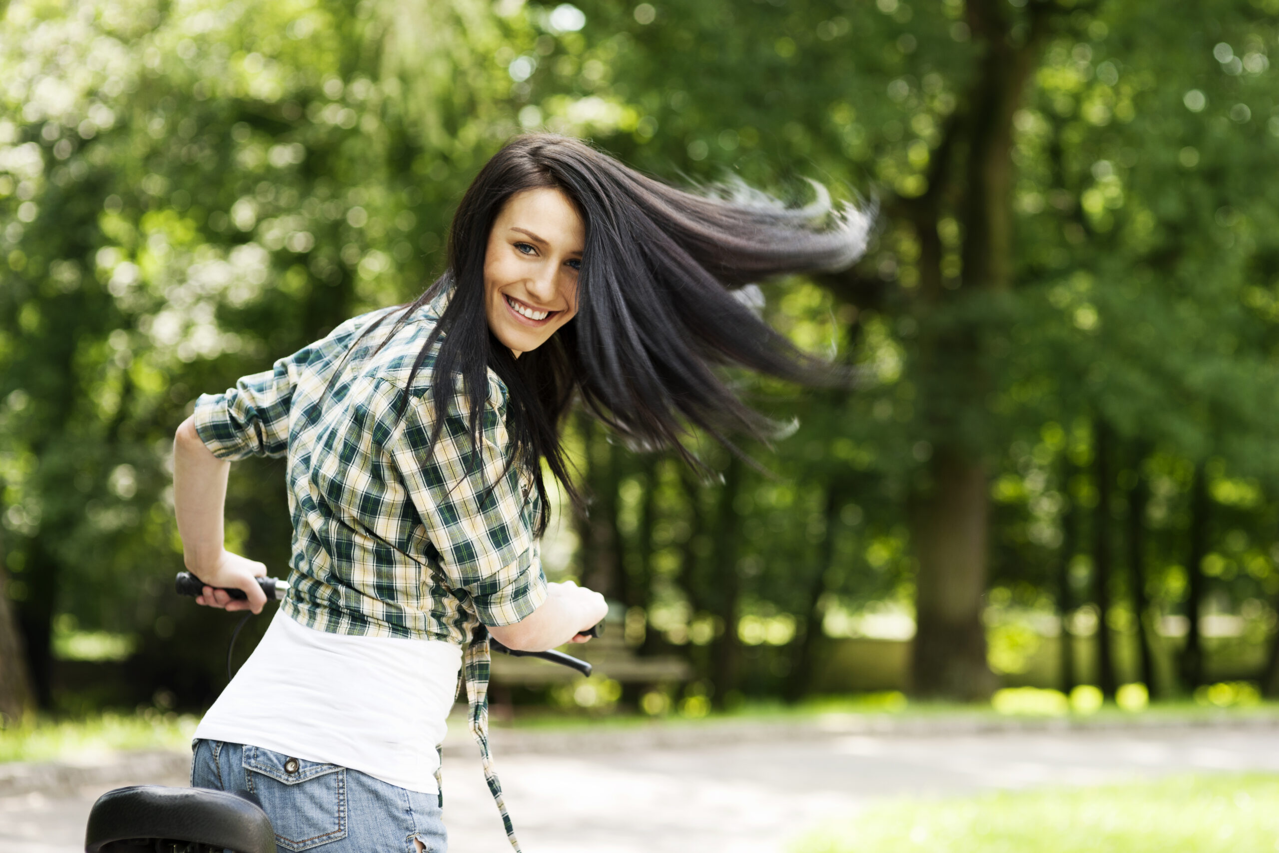 Happy young woman with bike in the park